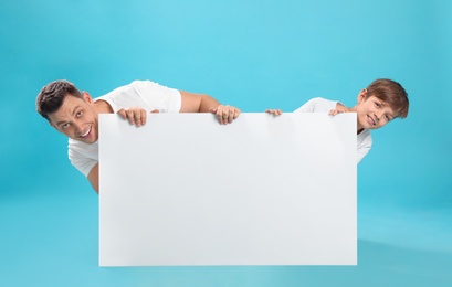 Photo of Dad and his son with empty banner on color background. Space for design