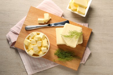 Tasty butter with dill and knife on wooden table, flat lay