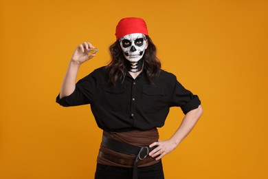 Man in scary pirate costume with skull makeup and gem on orange background. Halloween celebration