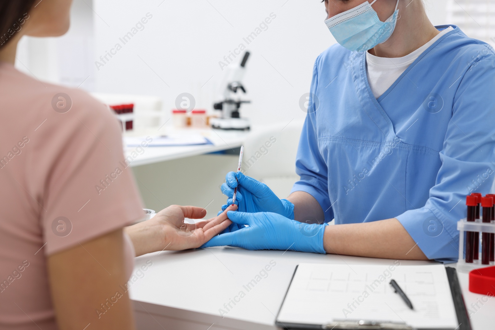 Photo of Laboratory testing. Doctor taking blood sample from patient at white table in hospital, closeup