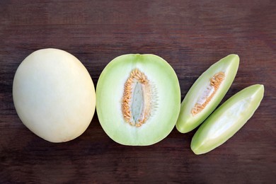 Tasty whole and cut ripe melons on wooden table, flat lay