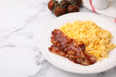 Photo of Delicious scrambled eggs with bacon in plate on white marble table. Space for text