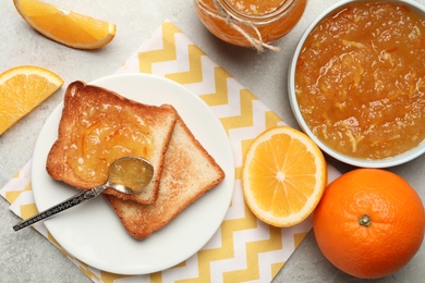 Photo of Delicious orange marmalade and toasts on light table, flat lay