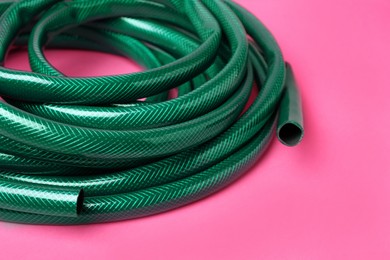 Watering hose on pink background, closeup view
