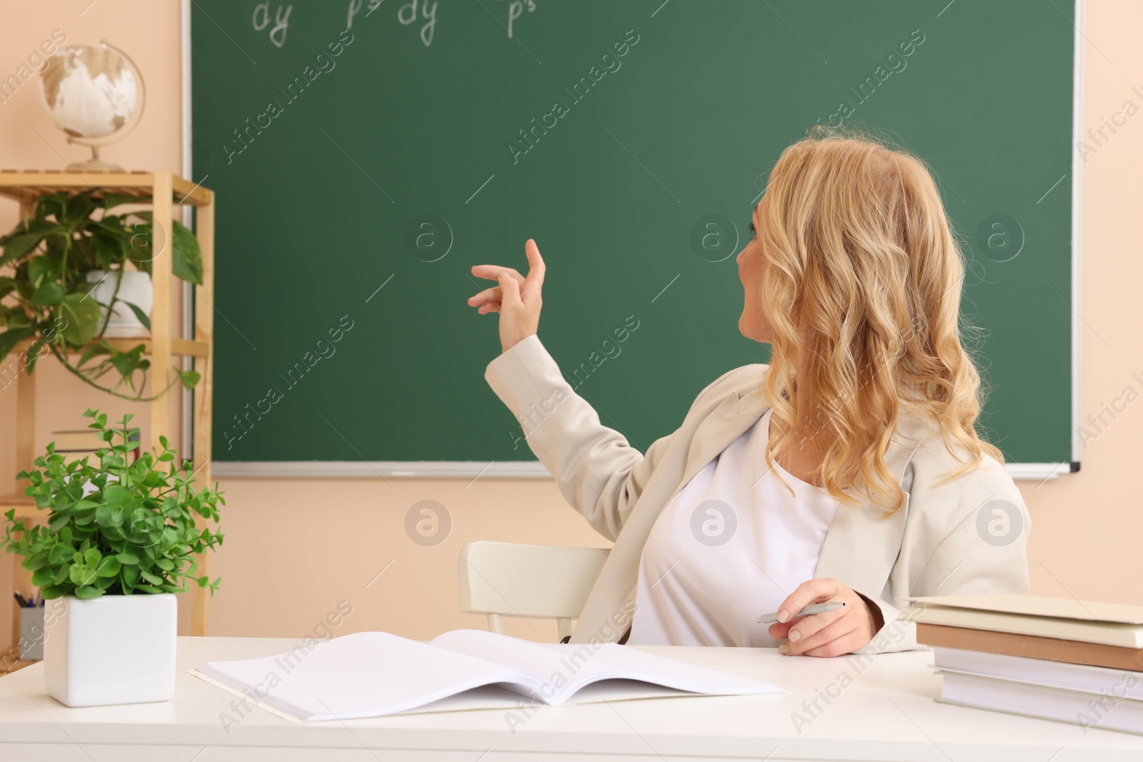 Photo of Professor pointing at green board with math equation in classroom