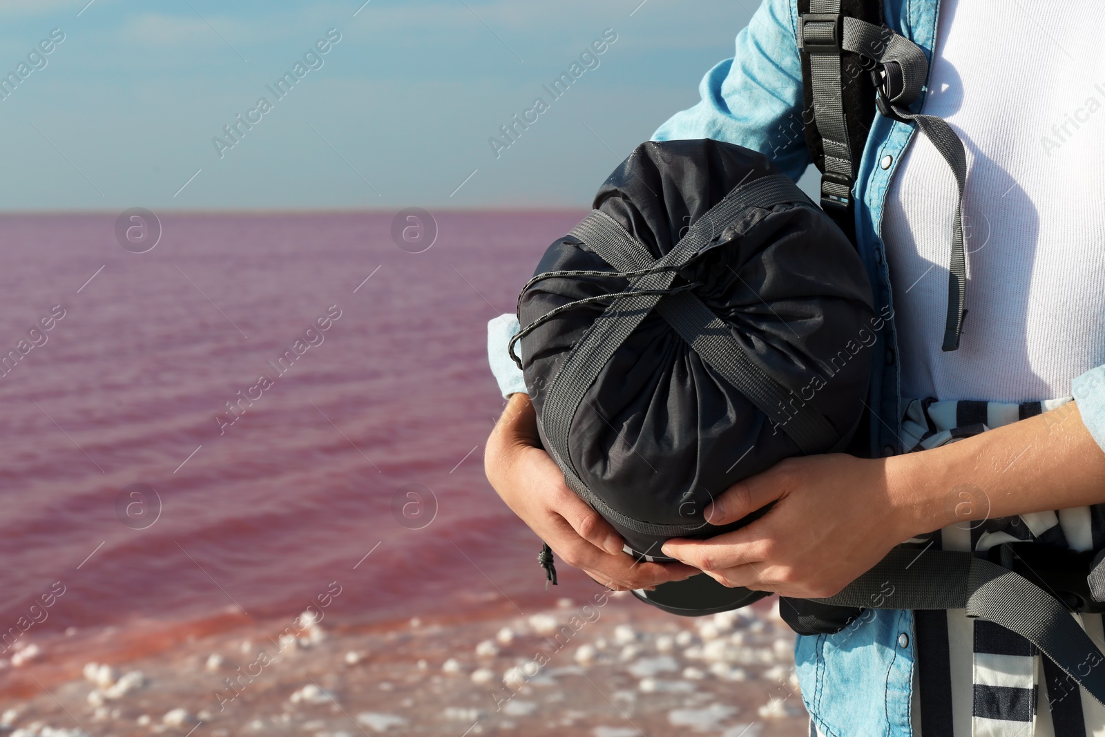 Photo of Woman with sleeping bag on coast of pink lake