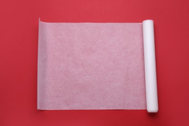 Photo of Roll of baking paper on red background, top view