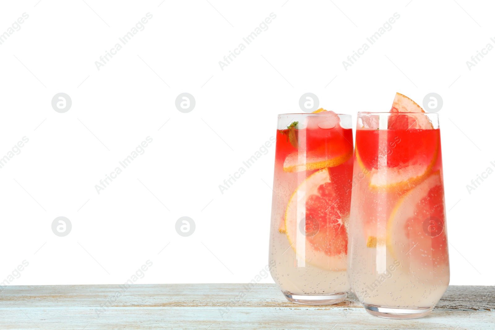 Photo of Glasses of grapefruit refreshing drink on wooden table against white background