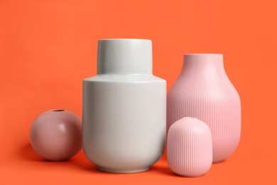 Photo of Stylish empty ceramic vases on orange background