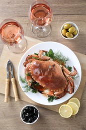Photo of Delicious crab with greens served on wooden table, flat lay