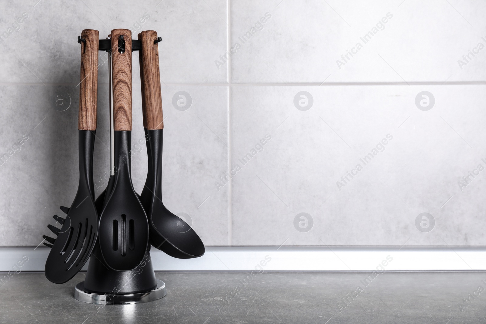 Photo of Holder with kitchen utensils on grey table. Space for text