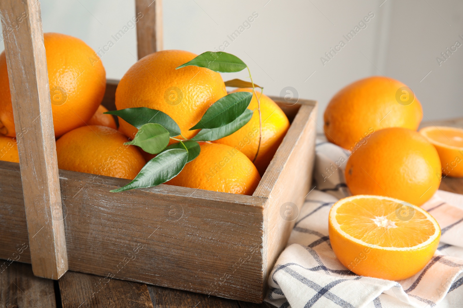 Photo of Fresh oranges with leaves and rustic box on wooden table