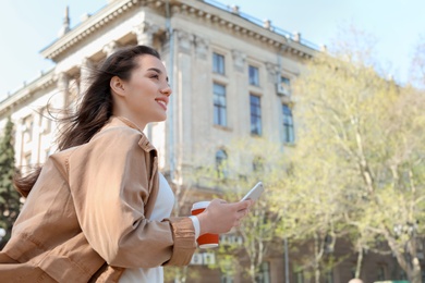 Photo of Young woman using phone outdoors on sunny day