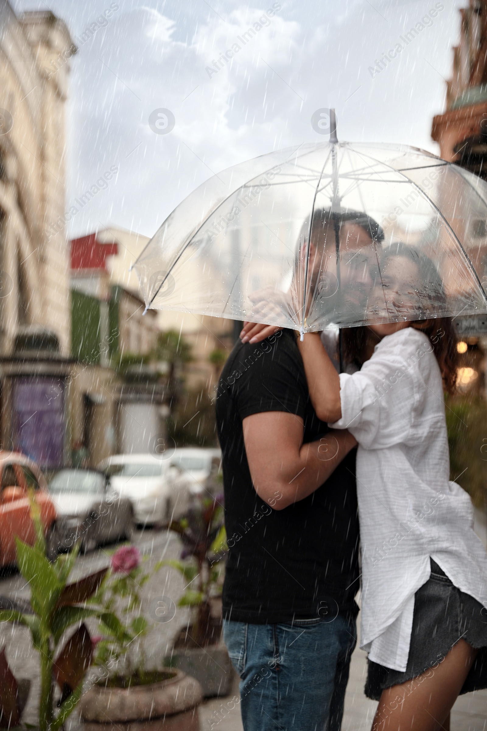 Photo of Young couple with umbrella enjoying time together under rain on city street