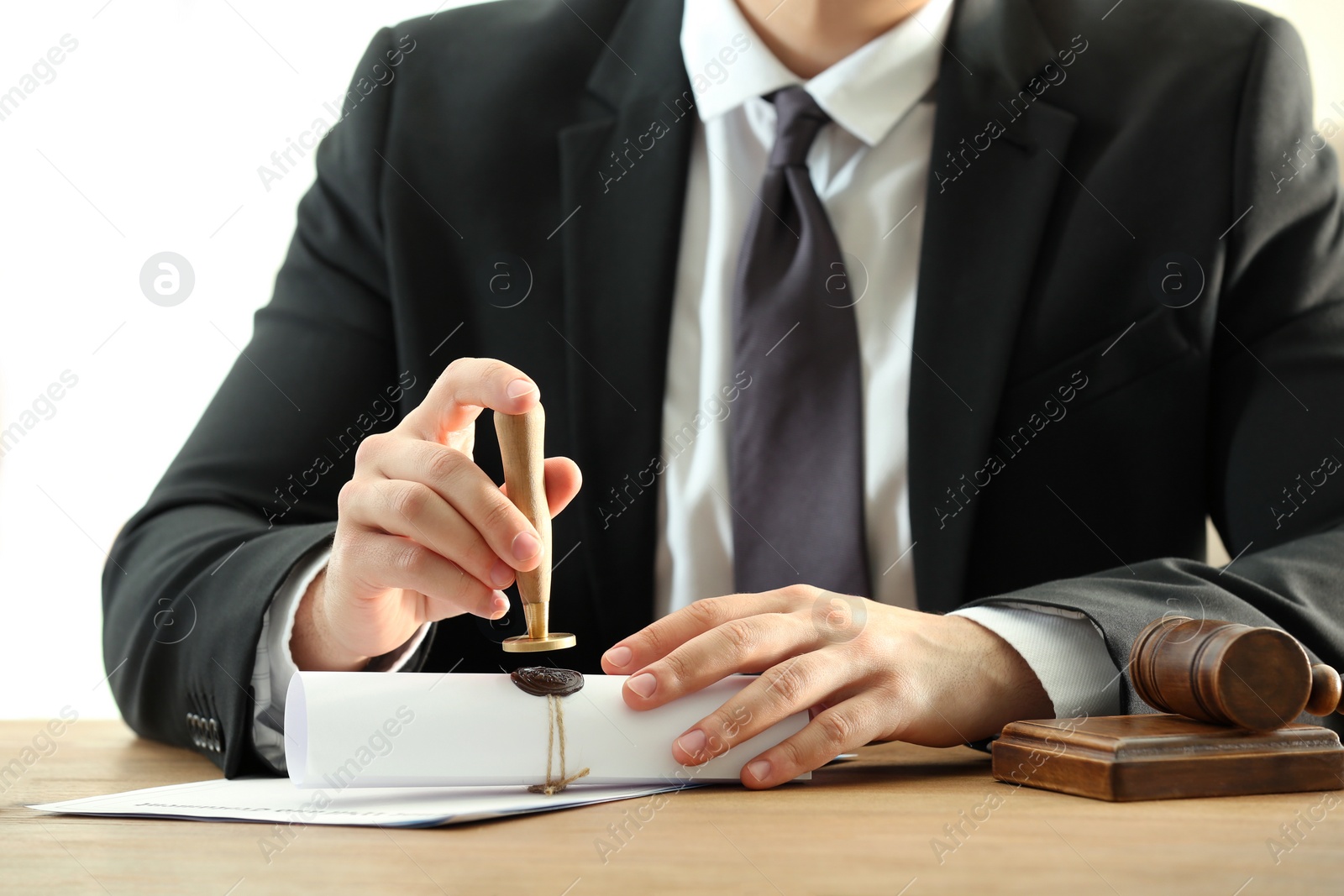 Photo of Male notary sealing document at table, closeup