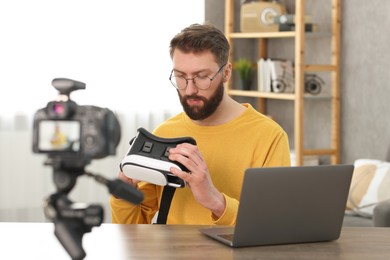 Photo of Technology blogger recording video review about virtual reality headset at home