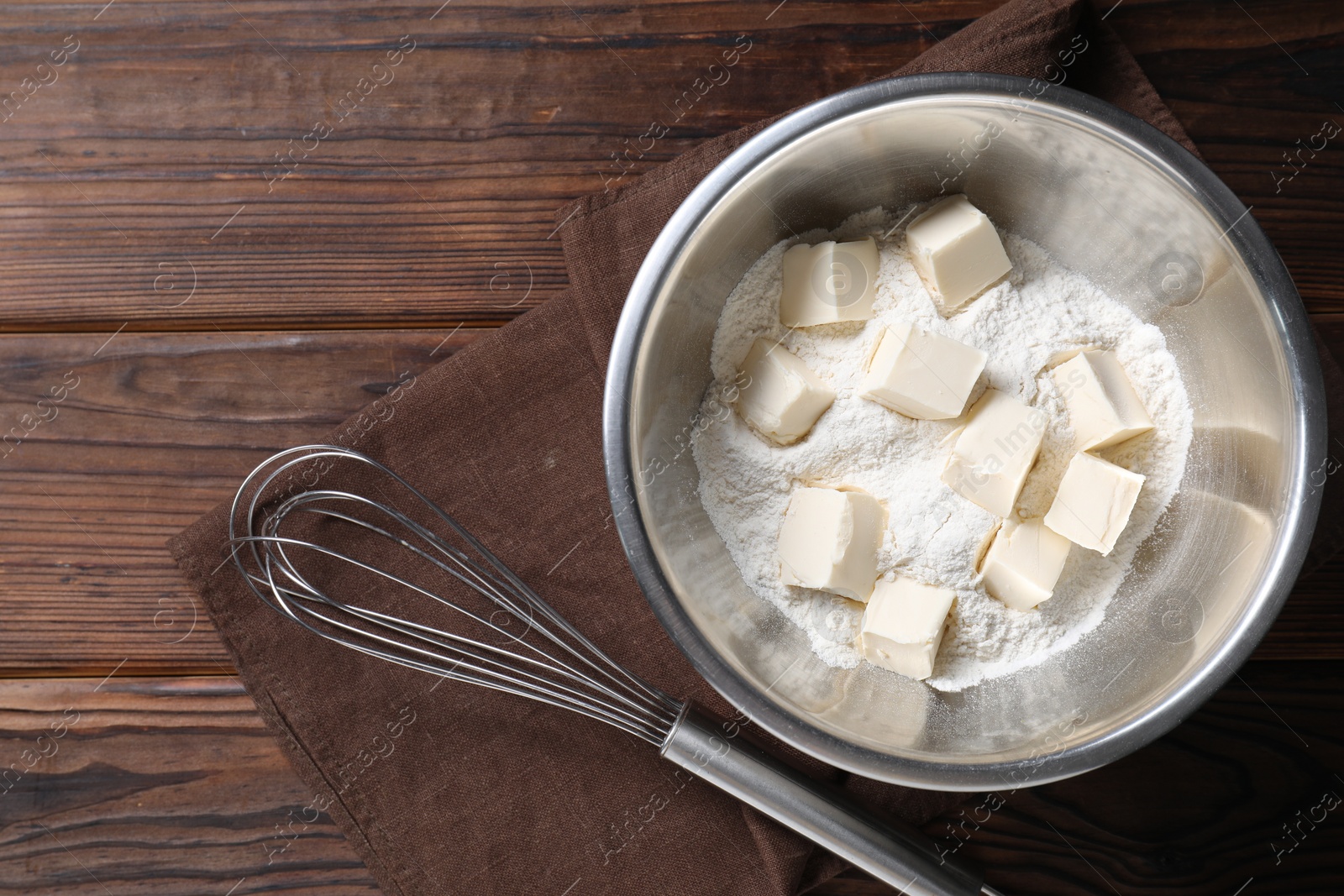 Photo of Making shortcrust pastry. Flour, butter and whisk on wooden table, top view