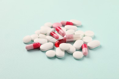 Photo of Pile of different pills on mint background, selective focus