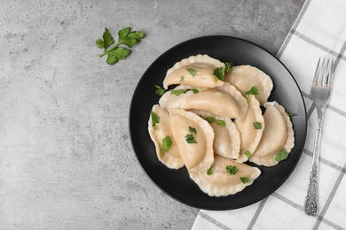 Photo of Plate of tasty dumplings and fork on stone surface, top view with space for text