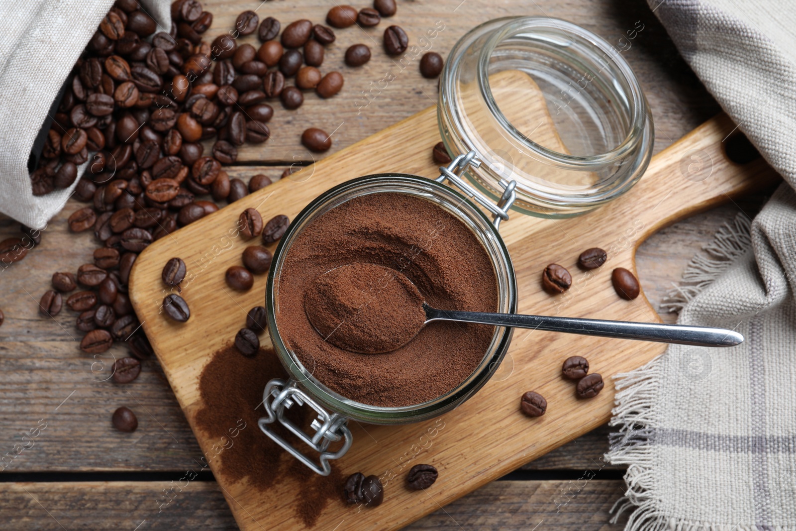 Photo of Glass jar of instant coffee and spoon on wooden table, flat lay