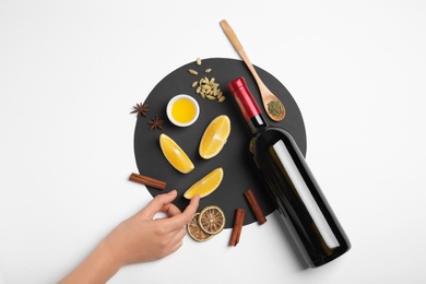 Photo of Woman arranging ingredients for mulled wine on white background