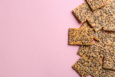 Photo of Delicious crackers on pink background, flat lay. Space for text