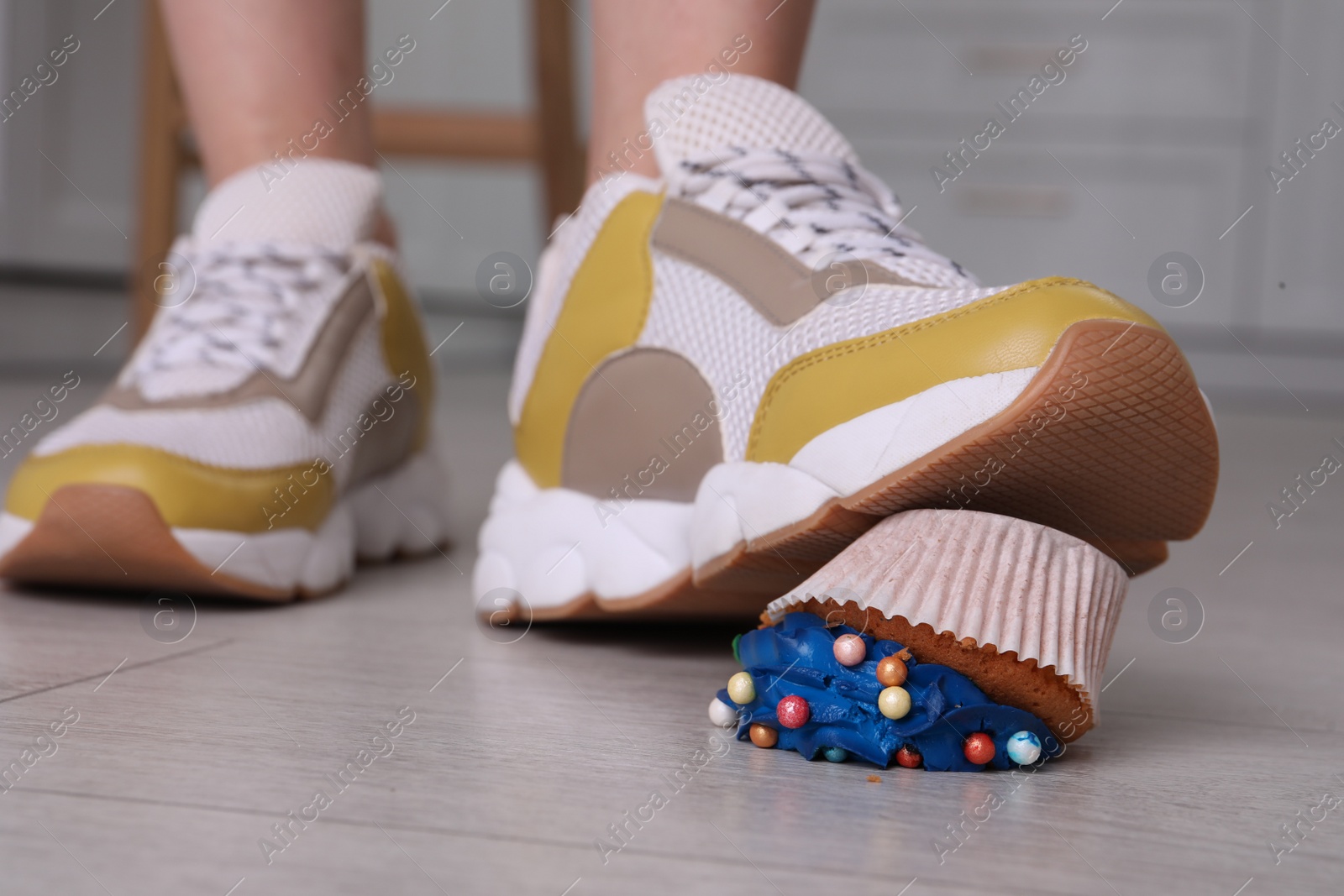 Photo of Woman stepping on dropped cupcake indoors, closeup. Troubles happen