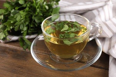 Photo of Aromatic herbal tea with parsley on wooden table, closeup