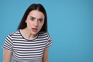 Photo of Portrait of surprised woman on light blue background. Space for text