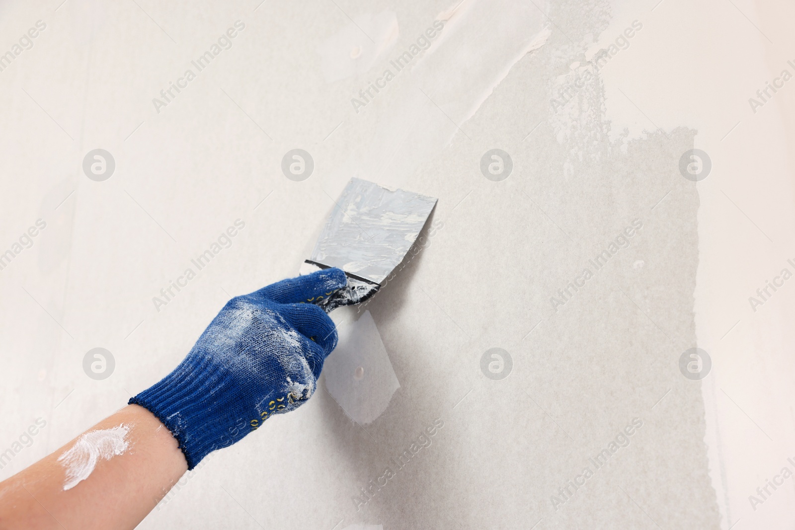 Photo of Man plastering wall with putty knife indoors, closeup. Home renovation