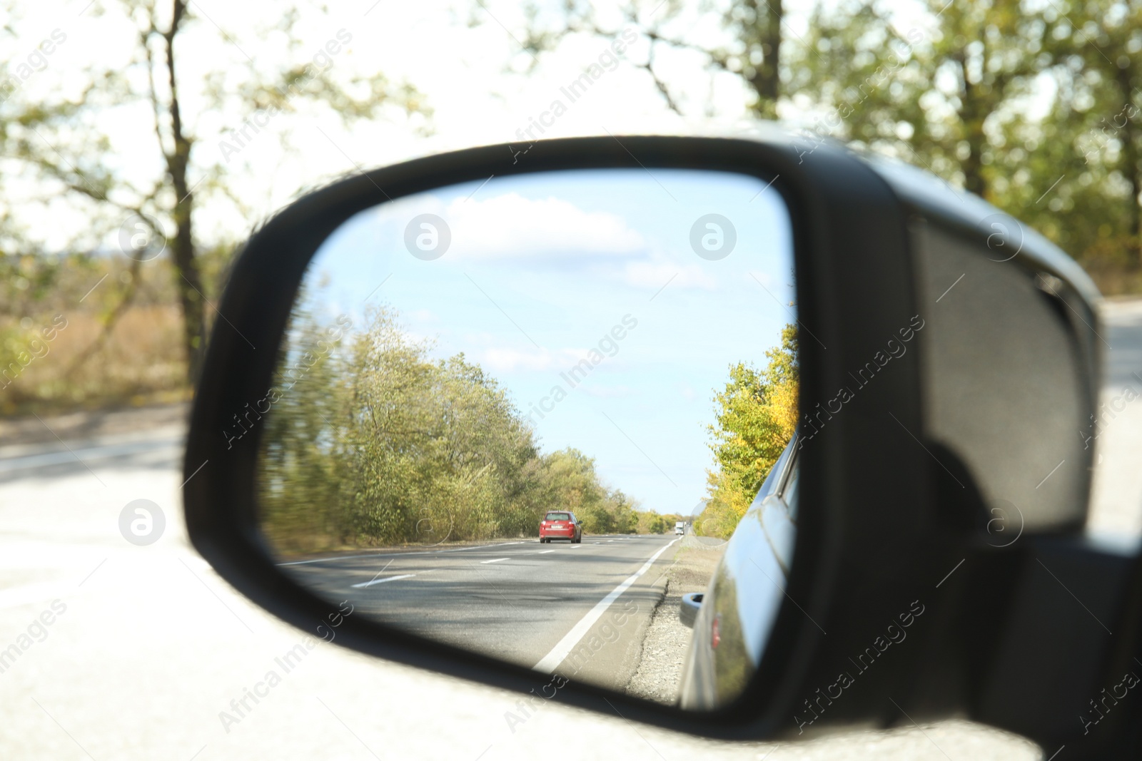 Photo of Closeup of car side rear view mirror on sunny day