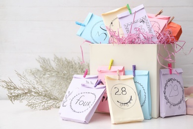 Photo of Colorful paper bags on white table, space for text. New Year advent calendar