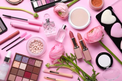 Photo of Flat lay composition with different makeup products and beautiful spring flowers on pink background