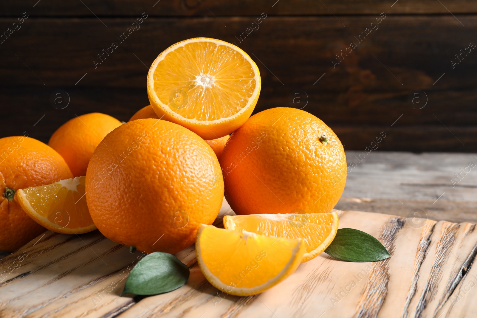 Photo of Fresh oranges with leaves on wooden table, space for text