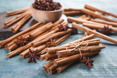 Photo of Aromatic cinnamon sticks and anise on blue wooden table