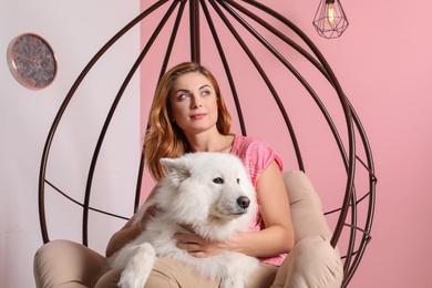 Photo of Beautiful woman with her dog sitting in swing chair at home