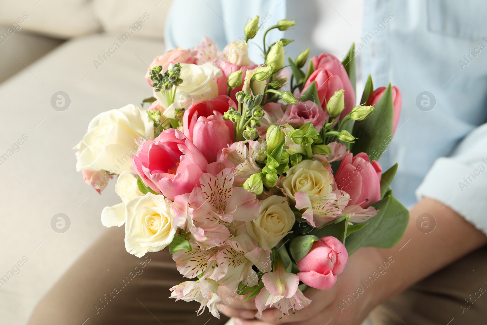 Photo of Man holding bouquet of beautiful flowers indoors, closeup