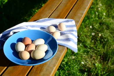 Plate and napkin with assorted eggs on wooden table outdoors