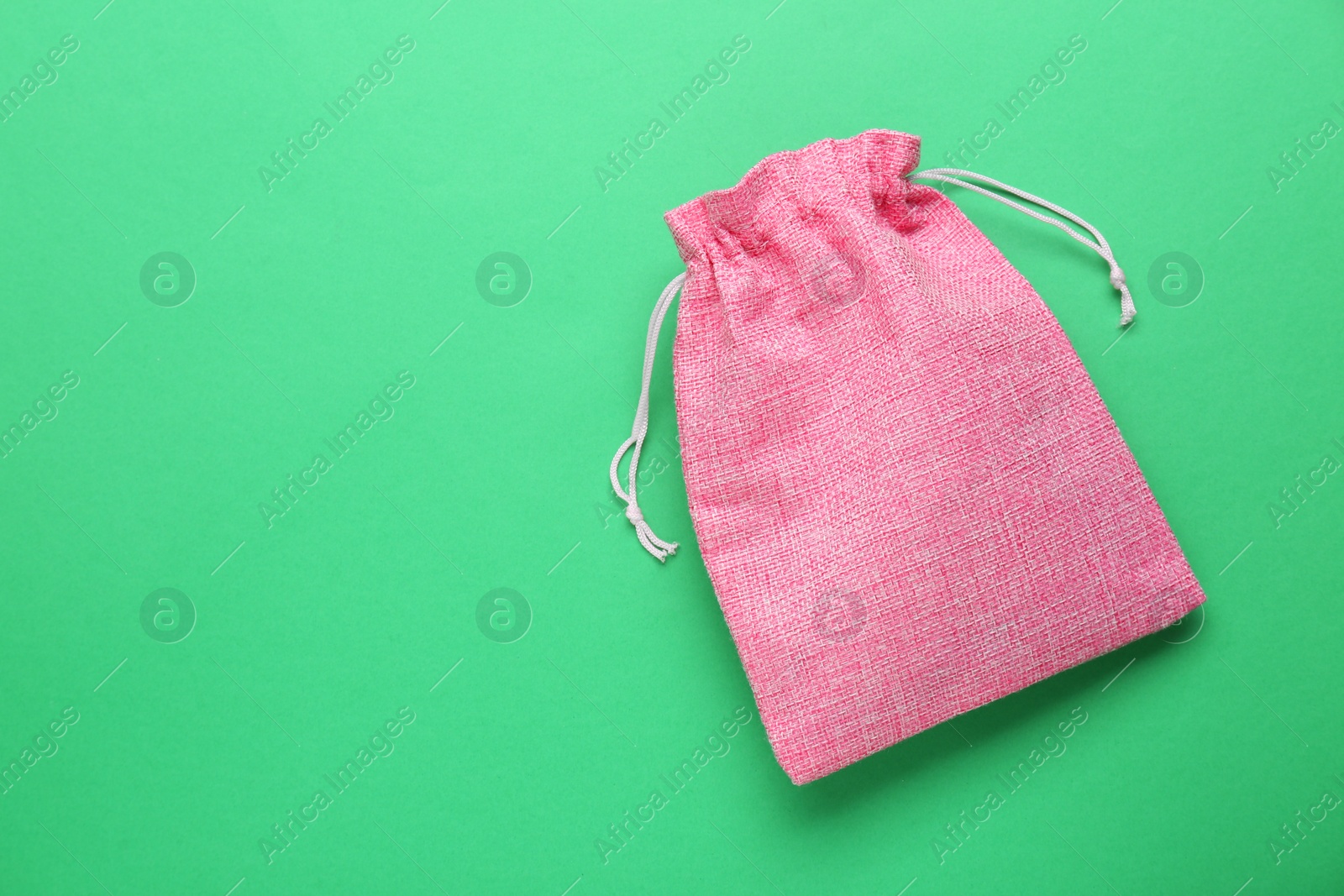 Photo of Pink burlap bag on green background, top view. Space for text