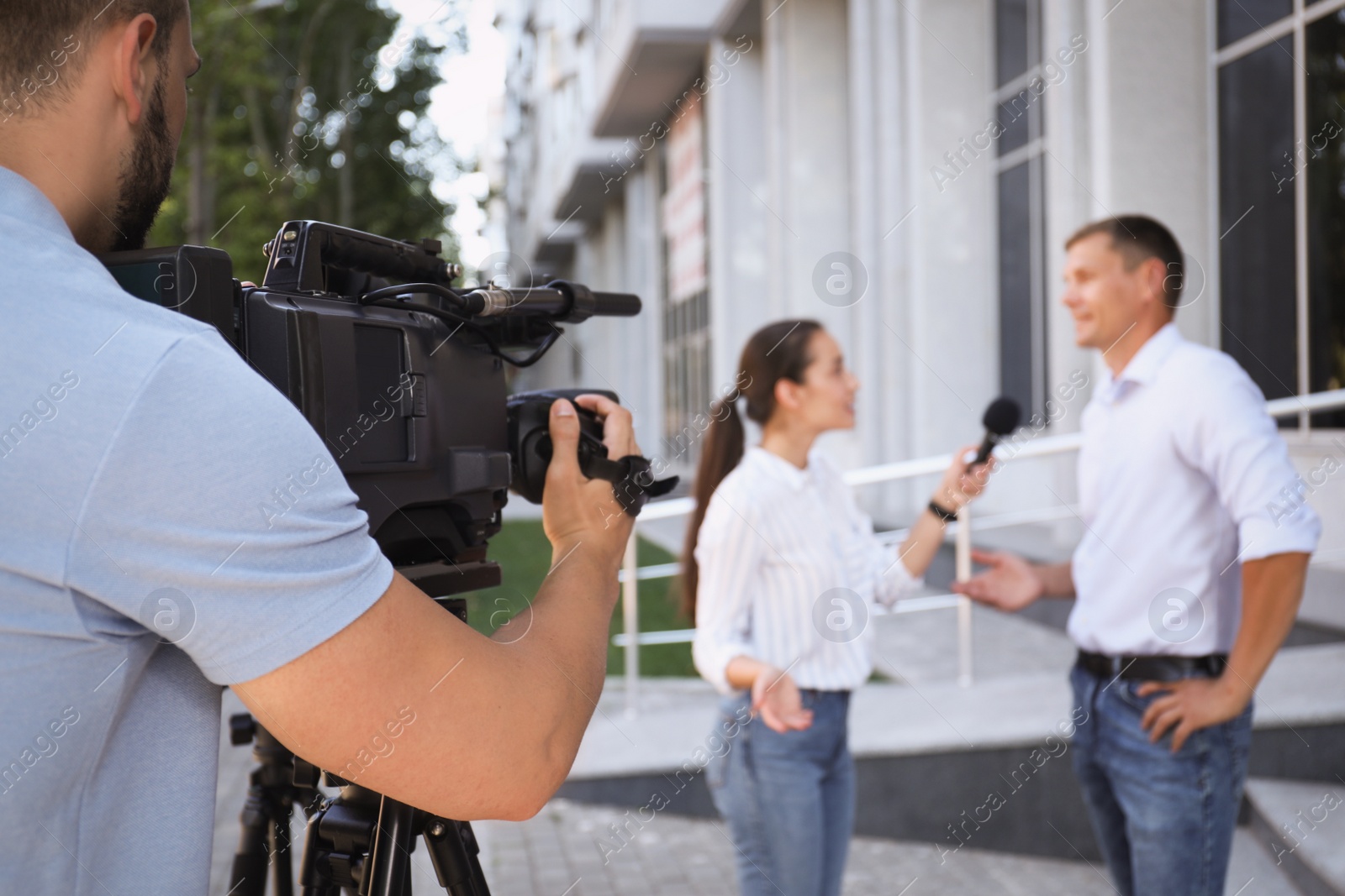 Photo of Professional journalist and operator with video camera taking interview outdoors