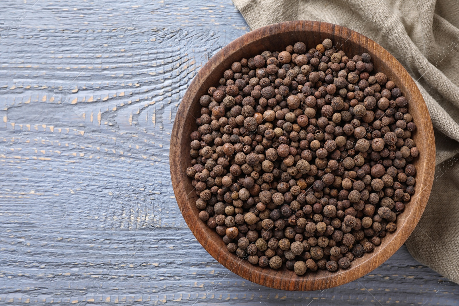 Photo of Bowl with peppercorns on wooden table, flat lay