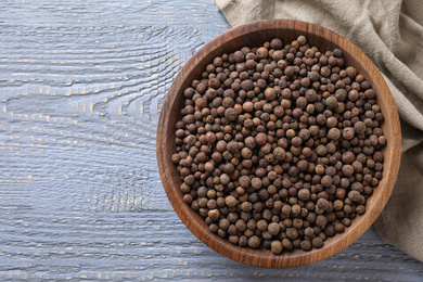 Photo of Bowl with peppercorns on wooden table, flat lay