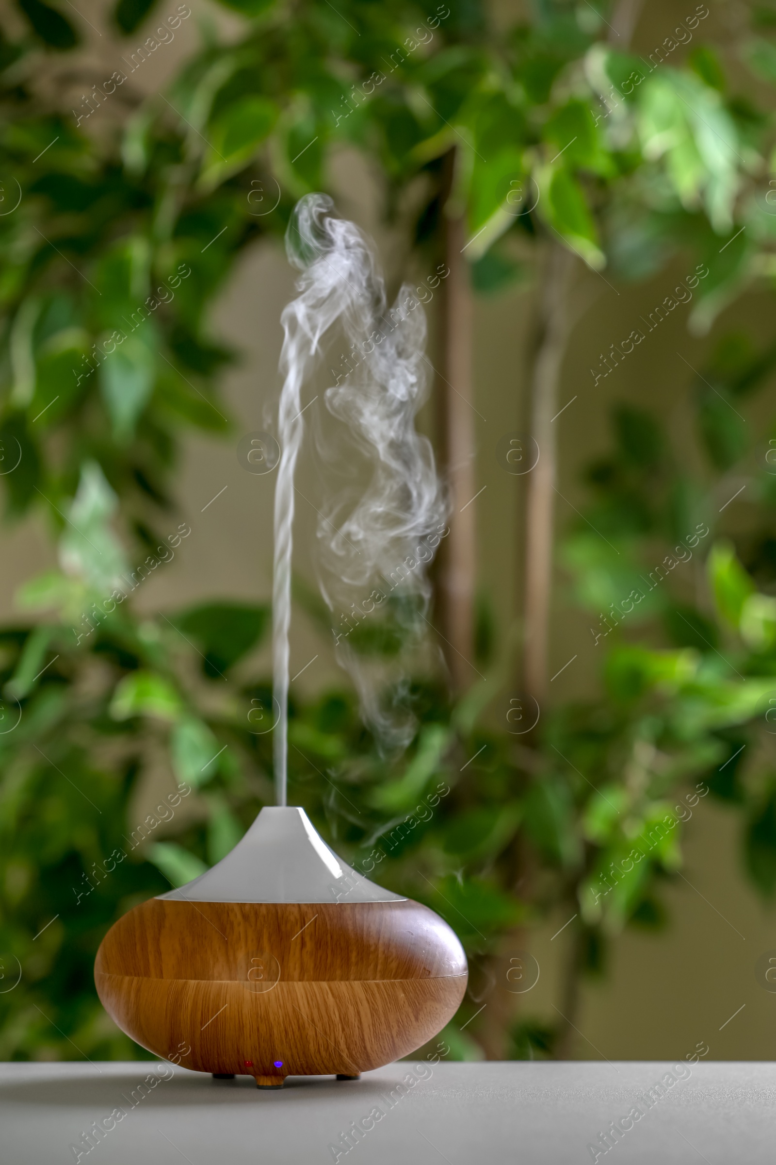 Photo of Aroma oil diffuser lamp on table against blurred background