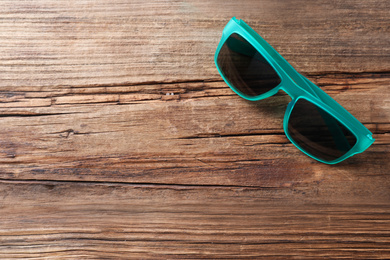 Photo of Stylish sunglasses on wooden background, top view. Space for text