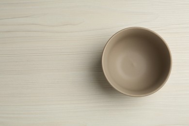 Photo of Stylish empty ceramic bowl on white wooden table, top view and space for text. Cooking utensil