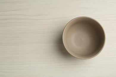 Stylish empty ceramic bowl on white wooden table, top view and space for text. Cooking utensil