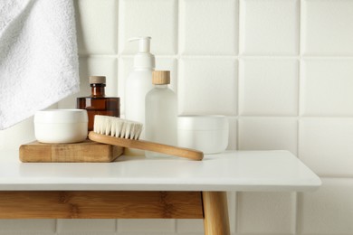 Different bath accessories and personal care products on white table near tiled wall