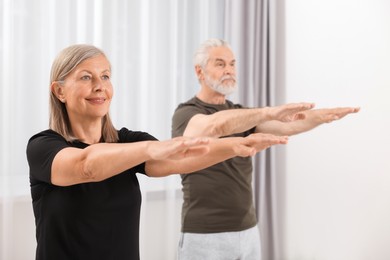 Photo of Senior couple practicing yoga at home, selective focus