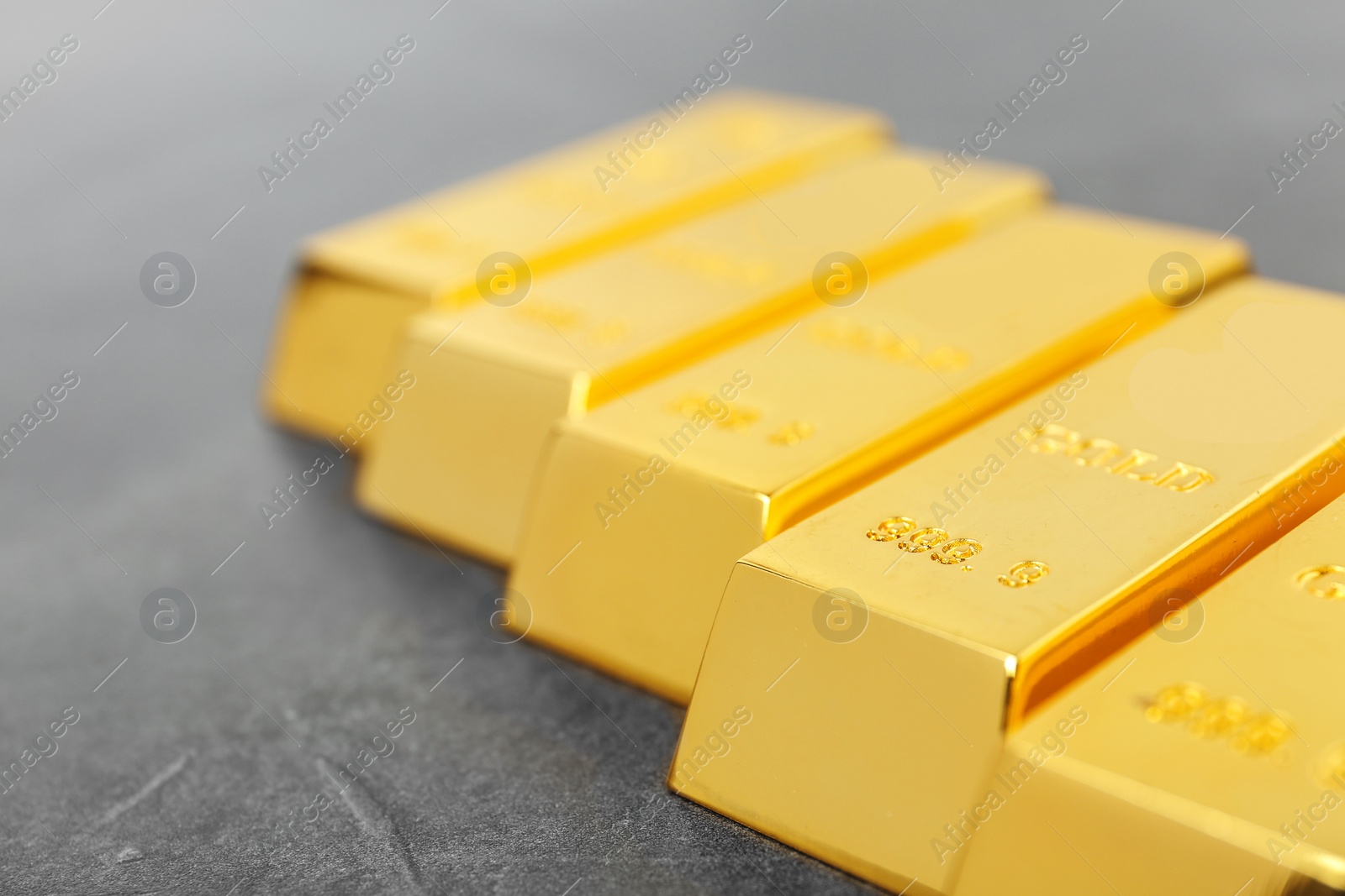 Photo of Shiny gold bars on grey background, closeup