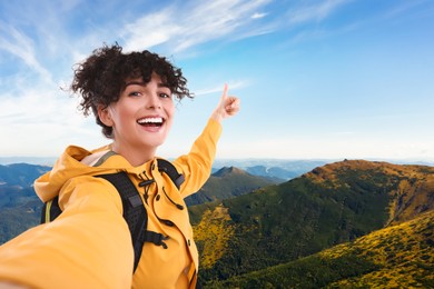 Beautiful young woman taking selfie in mountains
